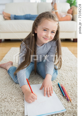 Happy girl drawing with her mother reading newspaper 7336228