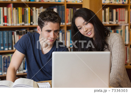 Two students learning in a library with a laptop Two students learning in a library with a laptop 7336303