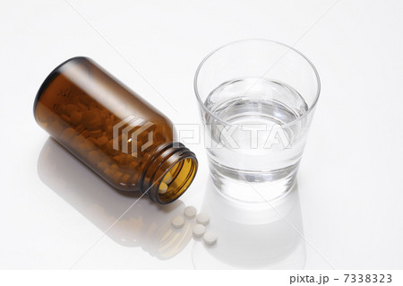 錠剤の入った薬ビンとコップの水 7338323