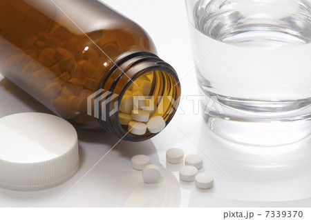 錠剤の入った薬ビンとコップの水 7339370