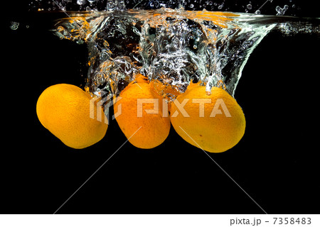 Fresh tangerines dropped into water with bubbles on black 7358483