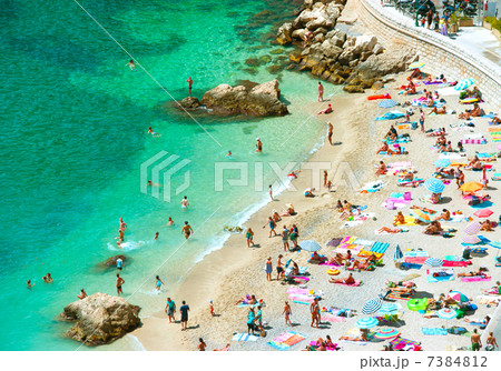beach of the Cote d'Azur with tourists with sunbeds and umbrella 7384812