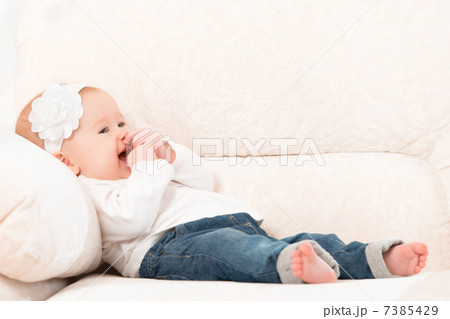 happy little baby girl laughing and sitting on a sofa in jeans 7385429