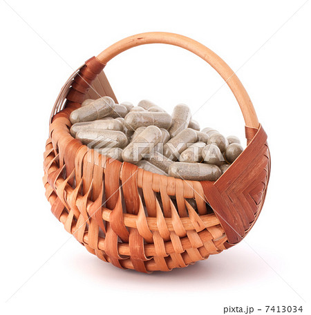 Herbal drug capsules in wicker basket. Alternative medicine conc 7413034
