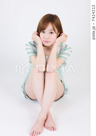 膝を抱えて座る若い女性 正面 の写真素材