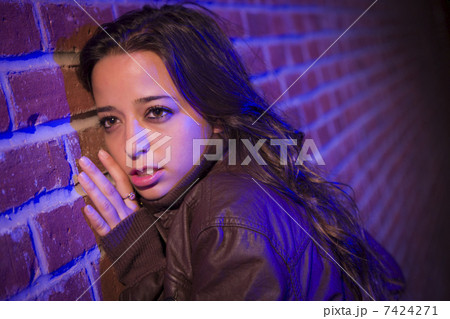 Frightened Pretty Young Woman Against Brick Wall at Night 7424271