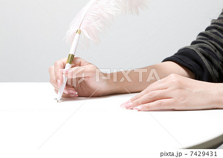 羽ペンを持つ女性の手の写真素材