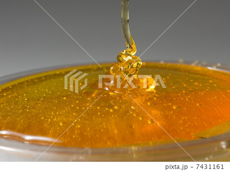 Golden honey flowing in glass plat 7431161