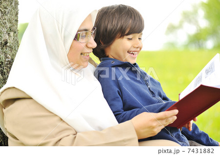 Mother Muslim and her son in the nature, reading together Mother Muslim and her son in the nature, reading together 7431882