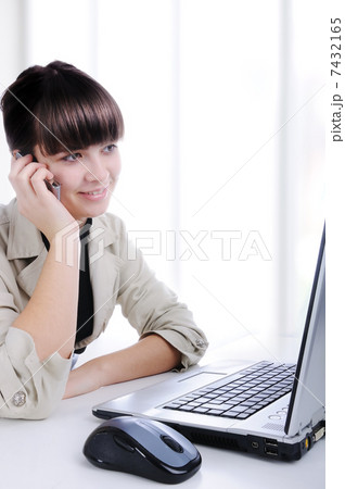 Portrait of a young woman on phone in front of a laptop computer 7432165