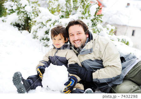 Father and son playing happily in snow making snowman, winter season 7432298