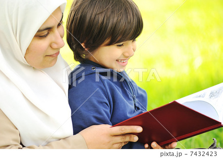 Mother Muslim and her son in the nature, reading together Mother Muslim and her son in the nature, reading together 7432423