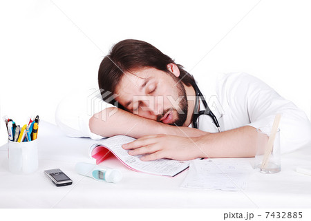 Young male doctor is sleeping on his desk in office 7432885