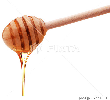 Honey dripping from a wooden honey dipper isolated on white back 7444981