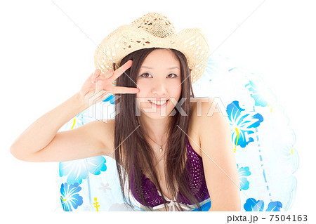 浮き輪に入ってピースをする麦わら帽子をかぶった女の子の写真素材