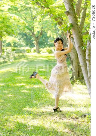 新緑眩しい初夏の森で木につかまって可愛いポーズをする女の子 7506020