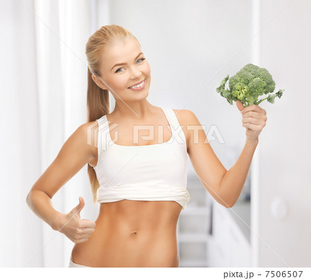 woman pointing at her abs and holding broccoli woman pointing at her abs and holding broccoli 7506507