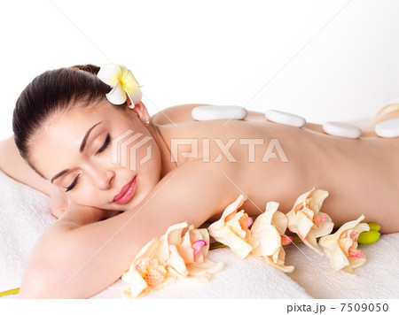 woman relaxing in spa salon with hot stones 7509050