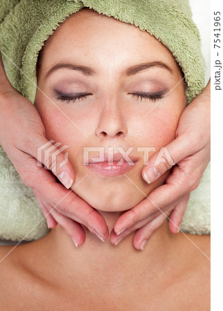 Young woman receiving facial massage 7541965