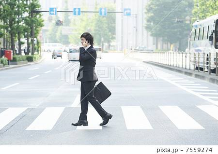 横断歩道を歩くスーツの男性の写真素材