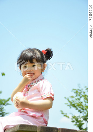 公園で肉まんを食べる女の子の写真素材