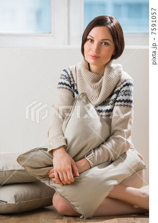 Portrait of a pretty brunette woman sitting on the floor with a 7591057