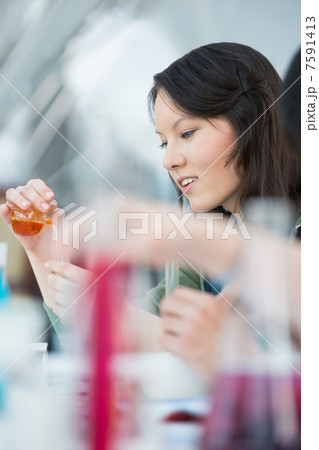 High School students. Pretty female student mixing reagents usin 7591413
