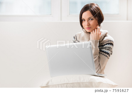 A young woman sitting on the floor in front of her laptop, looki A young woman sitting on the floor in front of her laptop, looki 7591627