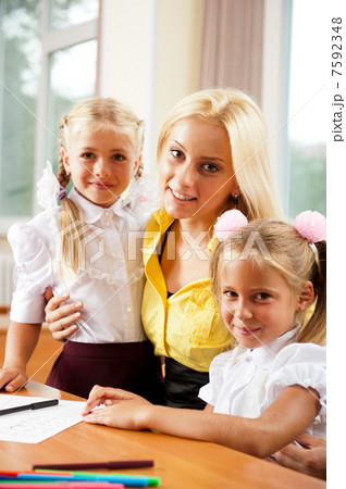 Young pretty teacher helping her little students in classroom 7592348