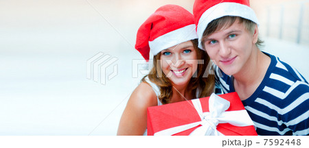 Portrait of young pretty couple standing indoors wearing Santa C Portrait of young pretty couple standing indoors wearing Santa C 7592448