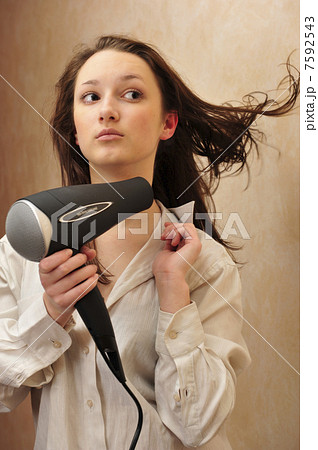Beautiful woman drying her hair with hairdryer 7592543
