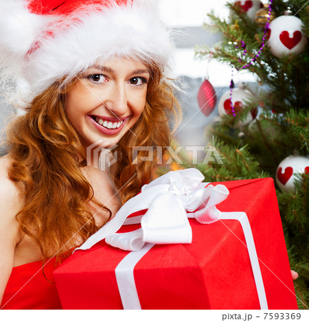 Christmas woman near a Christmas tree holding big gift box while Christmas woman near a Christmas tree holding big gift box while 7593369
