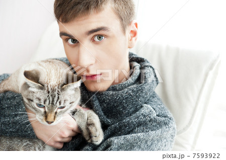 Relaxed man sitting on armchair holding and petting pet cat 7593922