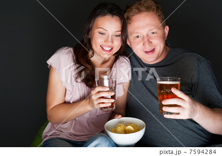 Happy couple sitting together watching something intresting on t 7594284