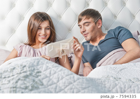 Young happy couple presenting gift in bed Young happy couple presenting gift in bed 7594335
