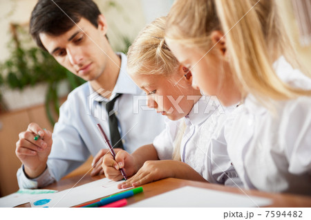 Teacher helping students with schoolwork in school classroom. Ho Teacher helping students with schoolwork in school classroom. Ho 7594482