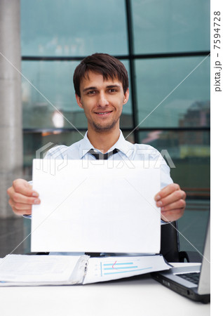 Attractive man in business suit with blank sign sitting at his o 7594728