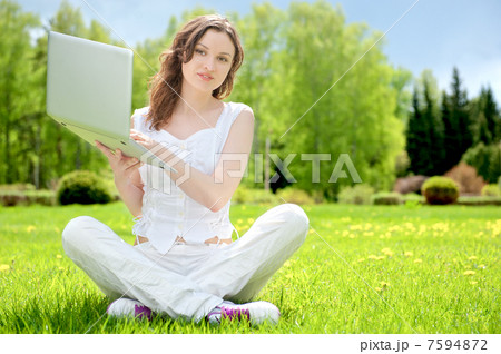 Young woman with laptop sitting on green grass Young woman with laptop sitting on green grass 7594872