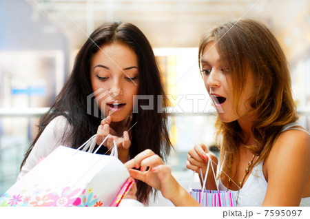 Two excited shopping woman together inside shopping mall. Horizo Two excited shopping woman together inside shopping mall. Horizo 7595097