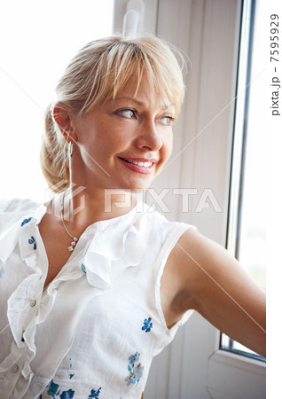 Closeup portrait of smiling woman standing near big window Closeup portrait of smiling woman standing near big window 7595929