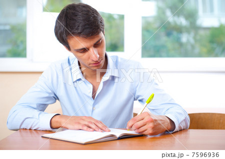 Businessman sitting indoors and writing plan in his diary 7596936
