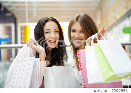 Two excited shopping woman together inside shopping mall. Horizo 7596948