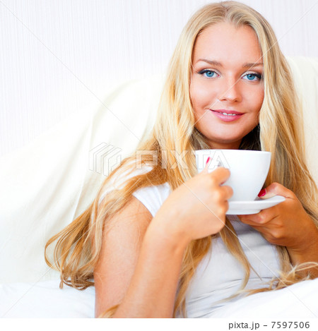 Smiling woman drinking a coffee lying on a bed at home or hotel. Smiling woman drinking a coffee lying on a bed at home or hotel. 7597506