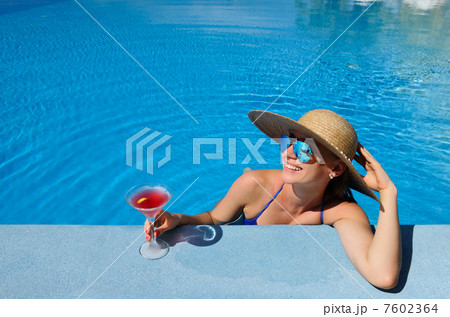 Woman at poolside with cosmopolitan cocktail 7602364