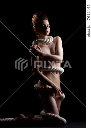 Slim naked girl wrapped by rope posing in studio 7611146