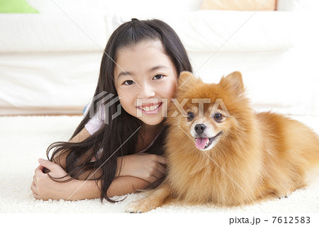 ポメラニアンと寝転がって微笑む女の子 7612583
