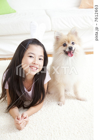 ポメラニアンと寝転がって微笑む女の子 7612663
