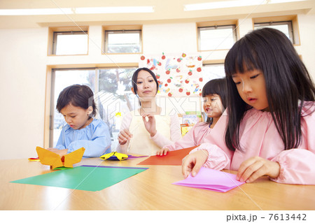 折り紙を折る幼稚園児と幼稚園教諭の写真素材
