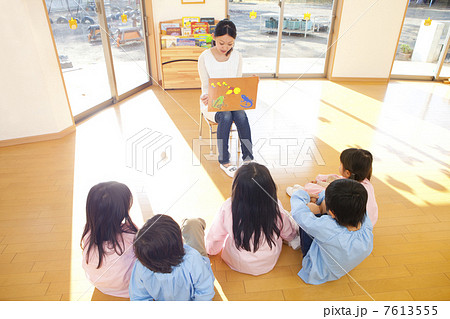 紙芝居に聞き入る幼稚園児5人の後姿 7613555