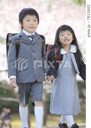 桜の下を歩く小学生男女 7613602